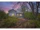 Charming single-story home with gray siding, blue trim, and mature trees under a colorful sky at 2022 S Clay St, Denver, CO 80219