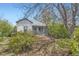 View of the home featuring gray siding, blue trim, and a welcoming covered front porch surrounded by lush greenery at 2022 S Clay St, Denver, CO 80219