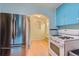 Efficient kitchen with stainless steel refrigerator, gas range, blue cabinets, and access to another room at 2022 S Clay St, Denver, CO 80219