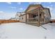 Snowy backyard with a wooden fence and home with covered patio at 144 Wooten Ave, Brighton, CO 80601