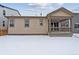 Private backyard with patio, covered porch and snowy lawn at 144 Wooten Ave, Brighton, CO 80601