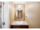 Powder room with a single sink, wood vanity, neutral walls, and a decorative round mirror at 9019 E Panorama Cir # D211, Centennial, CO 80112