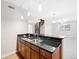 Wet bar including black granite countertops, a stainless steel sink, and wooden cabinets at 9019 E Panorama Cir # D211, Centennial, CO 80112
