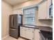 A kitchen with white cabinets, stainless steel refrigerator, and a window at 2902 W Long Cir # B, Littleton, CO 80120