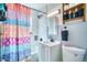Well-lit bathroom boasts a shower with bright colored shower curtain, a modern sink, and stylish shelving at 5610 Brentwood St, Arvada, CO 80002