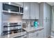 Kitchen with stainless steel appliances, granite counters, grey cabinets, and modern lighting at 5610 Brentwood St, Arvada, CO 80002