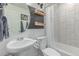 Modern bathroom features a pedestal sink, oval mirror, updated fixtures, and tiled shower at 10102 Yampa Ct, Commerce City, CO 80022