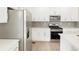 A modern kitchen featuring stainless steel appliances, white cabinetry, gray backsplash and light wood floors at 791 N Tempe St, Aurora, CO 80018