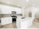 A modern kitchen featuring stainless steel appliances, white cabinetry, center island, and stairs in the background at 791 N Tempe St, Aurora, CO 80018