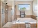 Close-up of the shower and tub with tile surround and a window bringing in natural light at 1264 Banner Cir, Erie, CO 80516