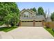 Charming two-story home showcasing a three-car garage and a beautifully landscaped front yard with mature trees at 17058 Hastings Ct, Parker, CO 80134