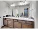 Bathroom featuring dual sinks, a large mirror, and wood cabinets at 19155 Robins Dr, Denver, CO 80249