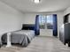 Bedroom with wood laminate flooring, large window with blue curtains and closet space at 19155 Robins Dr, Denver, CO 80249