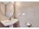 Powder room with a pedestal sink, round mirror, and neutral color palette at 9890 Gaylord St, Thornton, CO 80229
