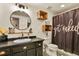 Bathroom with a stylish vanity, decorative mirror, wood shelves, and decorative shower curtain at 5405 S Sicily St, Aurora, CO 80015