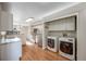 Spacious kitchen with modern stainless steel appliances, white cabinets and adjacent laundry area with front loading machines at 10329 W Fair Ave # C, Littleton, CO 80127