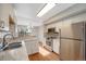 Open kitchen featuring stainless steel appliances, wood floors, and white cabinets with view to a dining area at 10329 W Fair Ave # C, Littleton, CO 80127