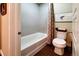 Bathroom with white tiled shower/tub combination, gray walls, and a white toilet at 15569 W La Salle Ave, Lakewood, CO 80228