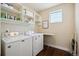 Functional laundry room with washer, dryer, shelving, and an ironing board at 15569 W La Salle Ave, Lakewood, CO 80228