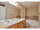 Well-lit bathroom featuring dual sinks, soaking tub and wood vanity at 9429 Ashbury Cir # 101, Parker, CO 80134