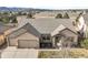 Inviting home exterior featuring stone accents, a covered entry, well-maintained landscaping, and an attached two-car garage at 1520 Symphony Hts, Monument, CO 80132
