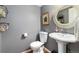 Charming powder room with pedestal sink, round mirror, and gray walls at 7142 S Hudson Ln, Centennial, CO 80122