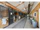 Horse barn aisle featuring multiple stalls and high ceilings, with visible wood beams and ample natural light at 39681 Swift Creek Cir, Elizabeth, CO 80107