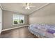 Bedroom with light walls, wood floor, ceiling fan and a window overlooking the greenery at 39681 Swift Creek Cir, Elizabeth, CO 80107
