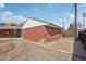 Brick back exterior featuring a gravel yard, a fence, and a clear sky at 7180 Zuni St, Denver, CO 80221