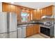 Well-lit kitchen with stainless steel appliances, wood cabinets, and granite countertops at 7180 Zuni St, Denver, CO 80221