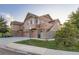 A well-maintained townhouse with tan and brown siding and stone accents and attached garages at 5757 S Algonquian Way # E, Aurora, CO 80016