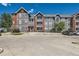 Three-story condo building with gray siding, brick accents, and convenient parking at 14251 E 1St Dr # 305, Aurora, CO 80011
