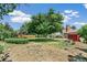 Backyard featuring a lush lawn, mature trees, and partial view of the home's exterior and deck at 8539 W Duquesne Dr, Lakewood, CO 80227