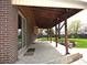 Covered brick back porch area featuring concrete flooring, wood beams, and space for outdoor seating at 11823 Williams Way, Northglenn, CO 80233