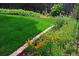 Landscaping showcasing colorful flowers and lush green lawn along the brick-lined garden at 11823 Williams Way, Northglenn, CO 80233