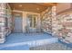 Inviting covered front porch with seating area, stone facade, and a well-maintained entrance at 7994 S Kewaunee St, Aurora, CO 80016