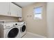 Convenient laundry room with modern washer and dryer, ample cabinet space, and a bright window at 16400 Alberta Dr, Parker, CO 80134