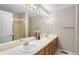Bathroom featuring a double sink vanity with wooden cabinets and a separate shower stall at 3205 S Tulare Ct, Denver, CO 80231