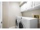 Functional laundry room with washer, dryer, and upper cabinets for convenient storage at 3205 S Tulare Ct, Denver, CO 80231