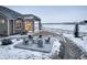 Backyard view of patio with seating, fire pit, and surrounding snow covered yard at 1060 Arrowhead Ct, Erie, CO 80516