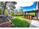 Landscaped backyard with mature trees, green lawn, stone water feature, and pergola-covered patio at 6762 Eagle Pl, Highlands Ranch, CO 80130
