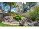 Landscaped backyard with a tiered rock feature, shrubs, and a wooden fence at 6762 Eagle Pl, Highlands Ranch, CO 80130