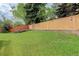 Large backyard featuring a wooden fence, stone retaining wall, and lush green grass at 354 Willowick Cir, Highlands Ranch, CO 80129