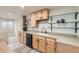 Basement bar area with modern sink, light wood cabinetry, sleek countertops, glass shelving, and natural light at 537 N 48Th Ave, Brighton, CO 80601