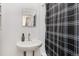 Compact bathroom featuring a pedestal sink, mirror, and a black and white patterned shower curtain at 4536 Beach Ct, Denver, CO 80211