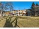 Attractive three-story apartment building with manicured lawn and mature trees against a clear, blue sky at 650 S Clinton St # 6D, Denver, CO 80247