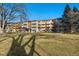 Well-maintained exterior view of the apartment building featuring mature trees and green lawn at 650 S Clinton St # 6D, Denver, CO 80247