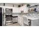 Efficient kitchen design with white cabinets, stainless appliances, light grey backsplash, and desk area at 650 S Clinton St # 6D, Denver, CO 80247