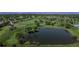 Aerial view of the well-manicured golf course with a serene pond, lush greens, and distant mountains at 6931 W 75Th Pl, Arvada, CO 80003