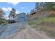 Exterior view of the detached garage with a gray metal roll up door and gravel driveway at 420 Chinook Rd, Idaho Springs, CO 80452